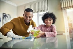 A young boy helping his father to clean the kitchen