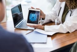 A doctor shows her patient a brain scan to explain a test result and diagnosis.