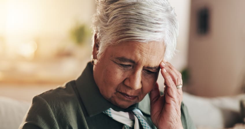 A woman holds her hand to her forehead as if she is struggling to recall something.