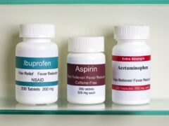 Bottles of otc pain relievers including ibuprofen, aspirin, and acetaminophen in a medicine cabinet