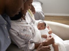A new mother sitting down while holding her baby in her arms