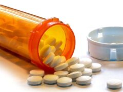 A prescription bottle containing nonsteroidal anti-inflammatory medicine spills out onto a table.