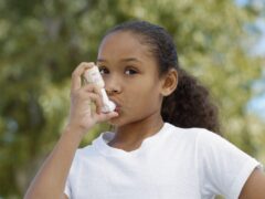 A girl using her metered-does asthma inhaler