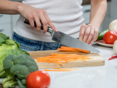 Close up of woman's hands cooking in the kitchen. Housewife slicing fresh carrot
