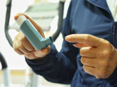 Asian female is opening cap of inhaler for using before exercise with blurred elliptical background.Medication for prevent bronchospasm or Dyspnea from asthma attack.Healthcare and medical concept.
