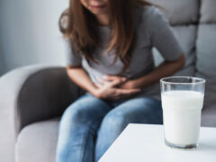 Woman having bad stomach ache with a glass of milk, Lactose intolerance, health care concept
