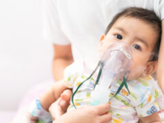 Close up of asian little baby boy is treated respiratory problem with vapor nebulizer to relief cough symptom in the hospital room , concept of pediatric patient care for sick in the hospital.