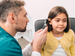 Ear exam. Pediatrician examining little mixed race child with otoscope, hearing exam of child