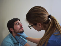 Healthcare worker palpating patient’s neck during exam