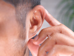 close up of young man holding ear suffering pain