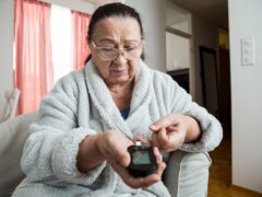 Senior woman checking blood sugar level using home glucometer. Old person with diabetes at home in living room.. Diabetes treatment for elderly people.