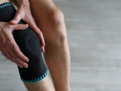 Man's legs with a knee pad for rehabilitation after injuries close-up.