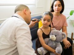 Pediatrician doing an examination and checking the ear of a sick child during a doctor's visit at home