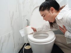 woman vomiting into toilet bowl in the bathroom