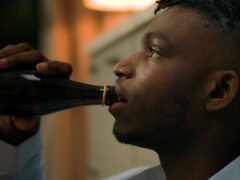 Addicted upset drunk African American depressed stress man drinking alcohol sad suffer problem drink beer with bottle ethnic guy biracial male addiction stressed mental worry bad habit home kitchen