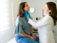 Young woman is undergoing a medical check-up as a doctor gently palpates her lymph nodes