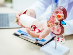 A male doctor sits at a desk in a hospital, explaining kidney models and symptoms of kidney disease, focusing on acute and chronic renal failure. Early detection supports effective treatment
