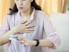Anxious patient touching her chest,measuring heartbeat with fingertip pulse oximeter,middle aged woman sweating,panicking,feeling tired,suffering from Thyrotoxicosis,Hyperthyroidism,overactive thyroid