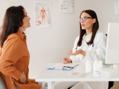 Medical specialist consulting middle aged female patient, complaining at abdominal pain due to pancreatitis, gastritis or diarrhea