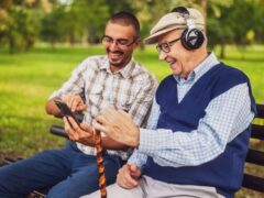 A grandpa and his grandson sit together in a park.