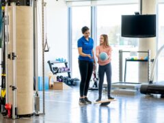A physical therapist working with a child athlete in a gym.