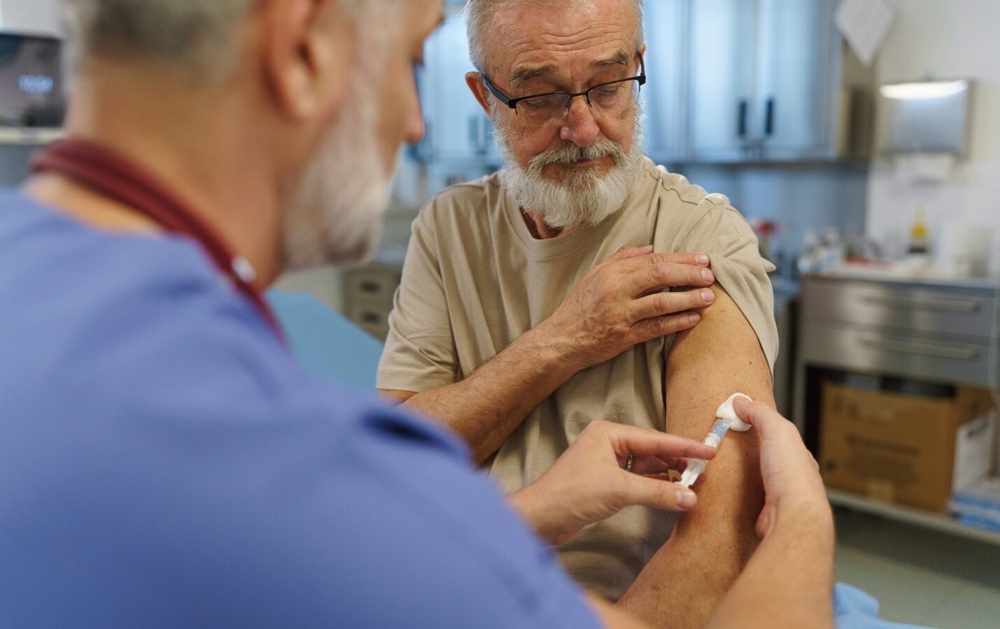 A family doctor giving a vaccine to an older patient.
