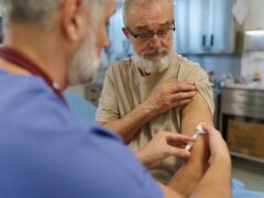 A family doctor giving a vaccine to an older patient.
