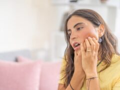 Woman rubbing mouth because of gum disease